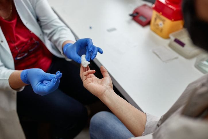 Lab technician takes a blood sample before from a finger to young woman before blood donation.