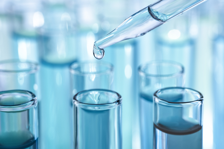 Photo shows laboratory glassware with dropper dripping liquid into test tube