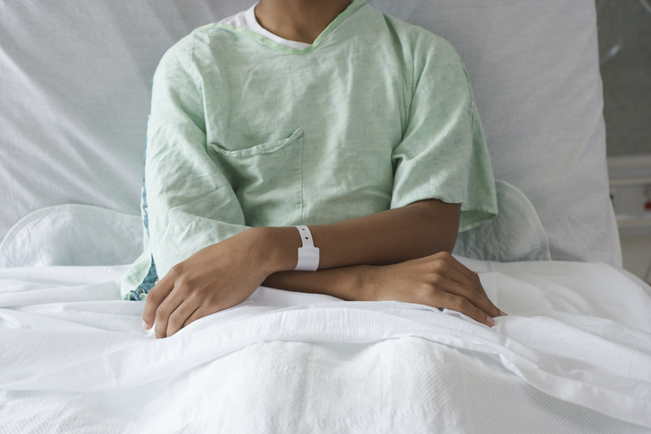 Photo shows male adolescent sitting in hospital bed