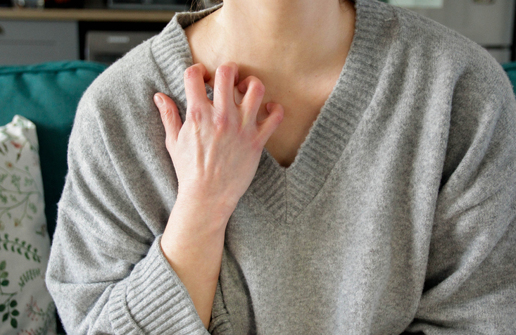 Photo shows woman scratching neck and chest