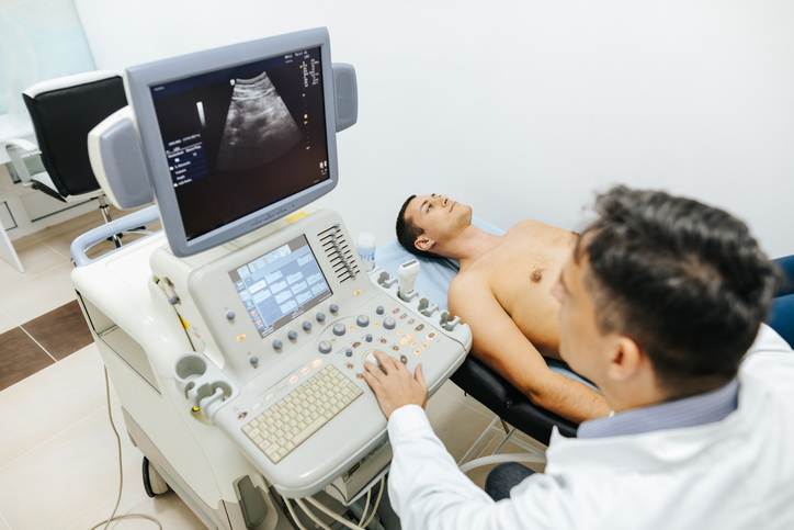 Photo shows patient having ultrasound examination of abdomen in medical clinic