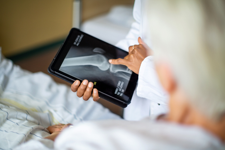 Photo shows doctor showing result of radiography on digital tablet to patient