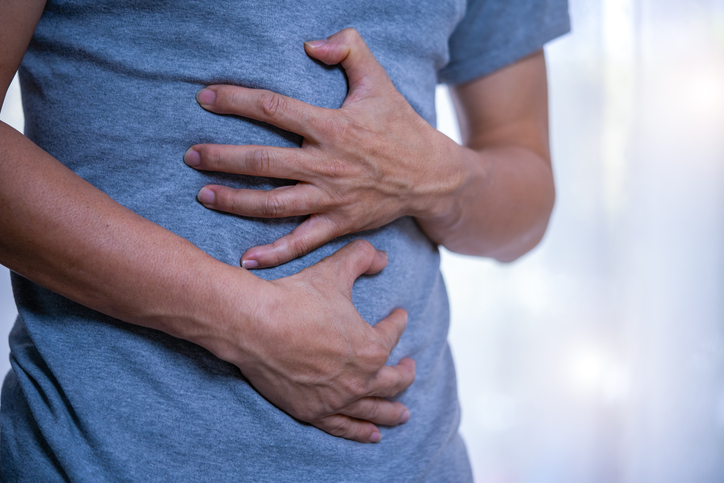 Photo shows a man holding his stomach due to stomach pain/Getty Images