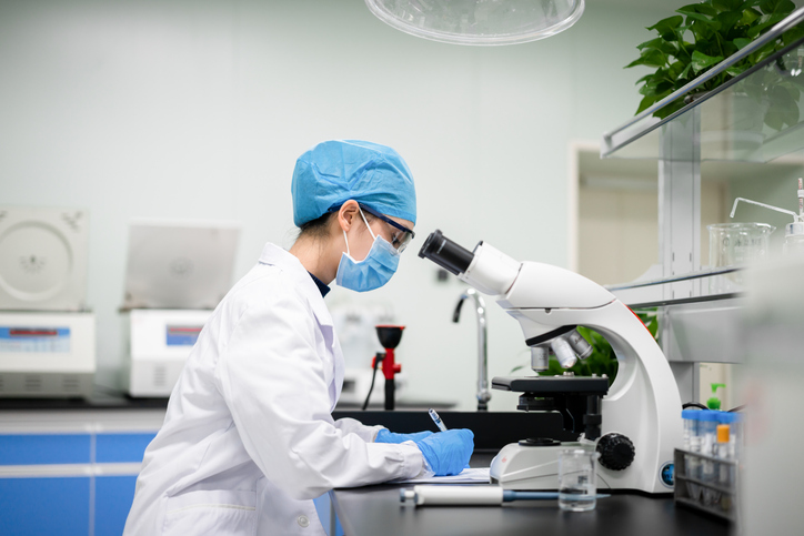 Photo shows a young doctor using a microscope in a lab/Getty Images