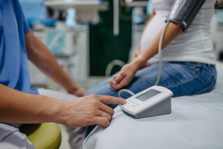 Photo shows a doctor measuring a pregnant patient's blood pressure/Getty Images